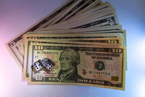 A stack of ten dollar bills with dice on top for a gambling concept Фото