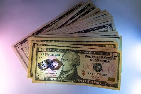 A Stack Of Ten Dollar Bills With Dice On Top Against Gradient Background Stock Photos