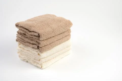 A stack of Terry towels white and light brown on a white background. Stock Photos