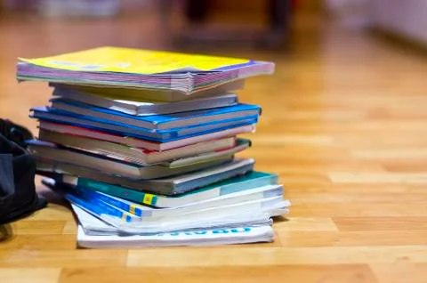 Stack of Textbooks and Black Backpack on Wooden Floor Foto stock