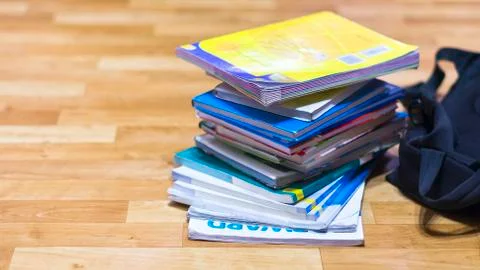 Stack of Textbooks and Black Backpack on Wooden Floor Stock Photos
