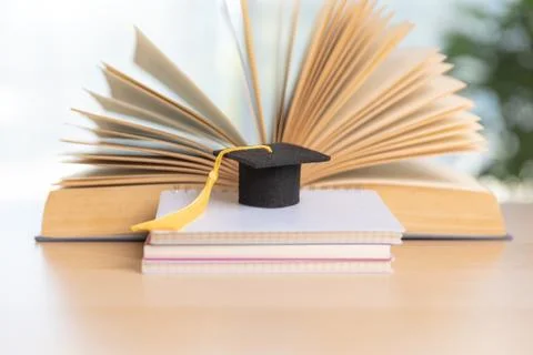 Stack of textbooks with graduation cap and red tassel beside pencil holder .. Stock Photos