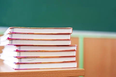 A stack of textbooks on a table against the backdrop of a school chalkboard.. Stock-Fotos