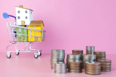 Stack of Thai Baht coin and colorful miniature houses on a shopping cart. Foto stock