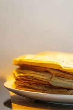 Stack of thin golden crepes on white plate Stock Photos