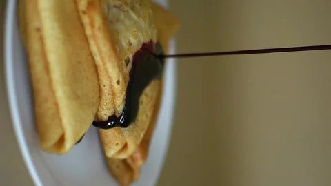 A stack of thin golden pancakes on a white platter, drizzled with sweet jam Stock Footage 305072633