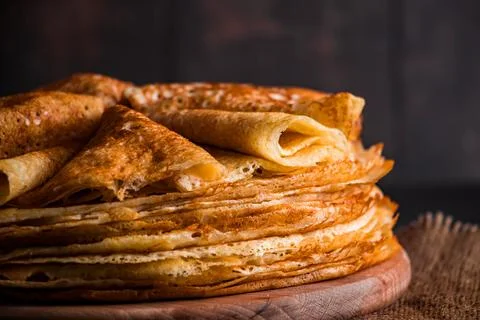 A stack of thin pancakes on a dark wooden background. A traditional dish of.. Stock Photos