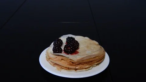 Stack of thin pancakes poured with honey and decorated with fresh blueberries Stock Footage 125545573