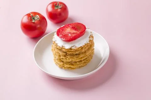 A stack of thin salty waffles with creamy sauce and tomato Stock Photos