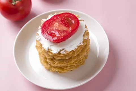 A stack of thin salty waffles with creamy sauce and tomato Stock Photos