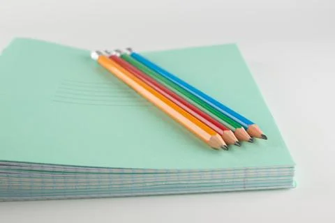 Stack of thin student notebooks with colored pencils Stock Photos