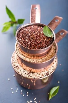 Stack of three copper measuring cups with mixed raw quinoa 스톡 사진
