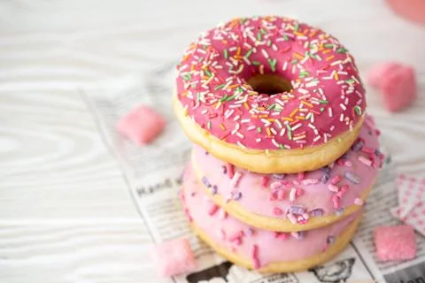 A stack of three donuts in glaze on a light background, top view Stock Photos