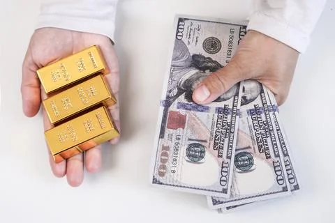 A stack of three fine gold bullion bars in the left open palm and a fanned .. Stock Photos