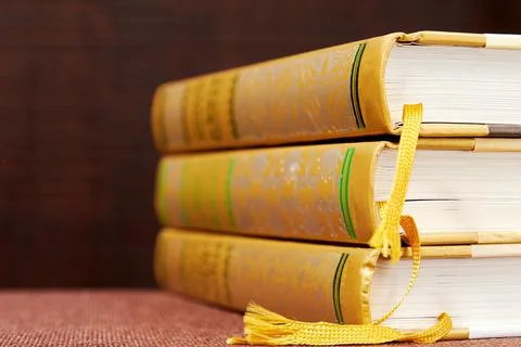 Stack of three hardcovered books on the bookshelf in the library Stock Photos