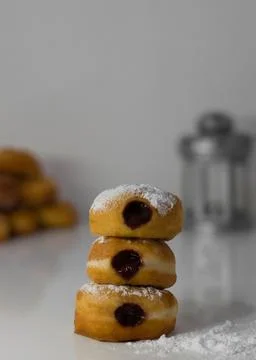 Stack of three jelly-filled doughnuts dusted with powdered sugar on a white Stock Photos