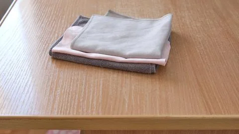 Stack of three neatly folded clean microfiber cloths in grey and pink on a light Stock Photos