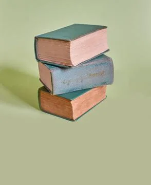 A stack of three old books lies on a plain background Stock Photos