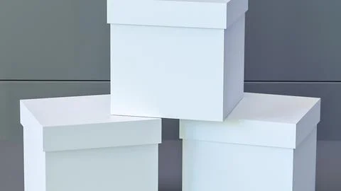 Stack of three plain white gift boxes with lids on a gray background Stock Photos