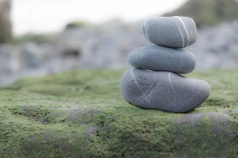 Stack of three rocks on a mossy surface Stock Photos