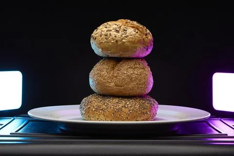 Stack of three seeded bread rolls with colorful lighting Stock Photos