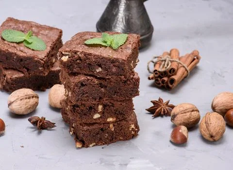 A stack of three square chocolate brownie pieces with walnuts, garnished wi.. Stock Photos