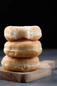 Stack of three sweet sugar donuts with bite mark on top Stock Photos