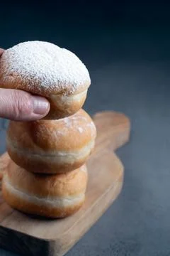 Stack of three traditional donuts with powdered sugar on a wooden board Stock Photos