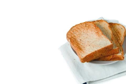 Stack of toast on white plate and white placemat on white background, top vie Stock Photos