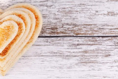Stack of toasted bread hearts on wooden table, concept of support in big family Stockfoto's