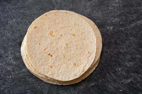 Stack of tortillas on a black table sprinkled with flour. Top view. Foto stock