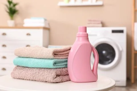 Stack of towels and detergent on table against blurred background Foto stock
