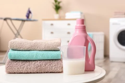 Stack of towels and detergent on table against blurred background 스톡 사진
