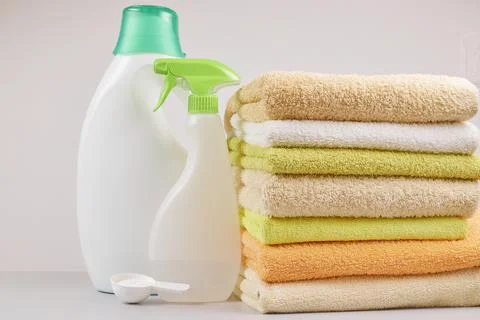 A stack of towels and laundry and bleach products on a light gray background Stock Photos