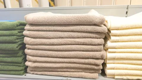 Stack of towels in different colors are on a shelf Stock Photos