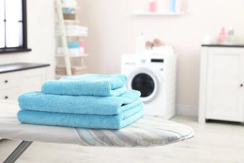 Stack of towels on ironing board against blurred background, space for text 스톡 사진