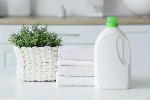 Stack of towels with laundry detergent and plant on table in room Stock Photos