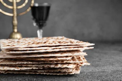 Stack of traditional matzos near red wine on grey table, closeup 스톡 사진