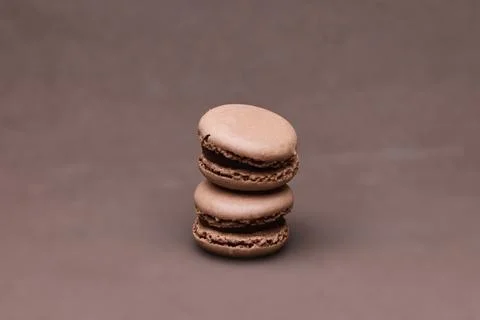Stack of two chocolate macarons isolated on brown background with copy space Stock Photos