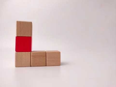 A stack of two wooden blocks topped with one red block sits beside two hori.. 库存照片