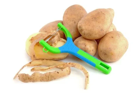 Stack of unpeeled potatoes and peeling knife Stock Photos