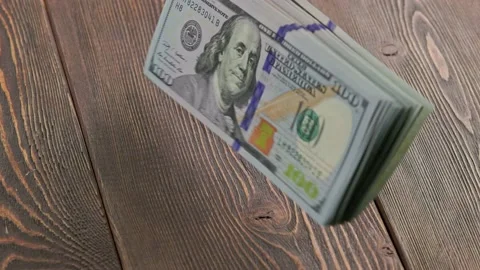 Stack of US dollar banknotes dropping on wooden surface and flipping Stock Footage 173902286
