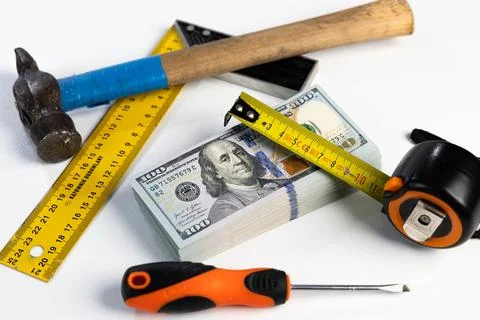 Stack of US dollar banknotes surrounded by construction tools on white back.. Stock Photos