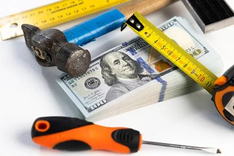 Stack of US dollar banknotes surrounded by construction tools on white back.. Stock Photos