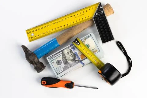 Stack of US dollar banknotes surrounded by construction tools on white back.. Stock Photos