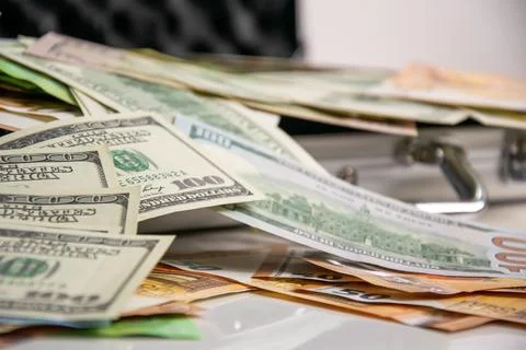 A stack of US dollar bills with a hundred dollar bill on top, resting on a si Stock Photos