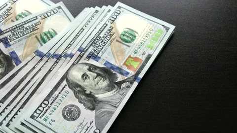 Stack of US hundred dollar bills falls on wooden table Stock Footage 148357513