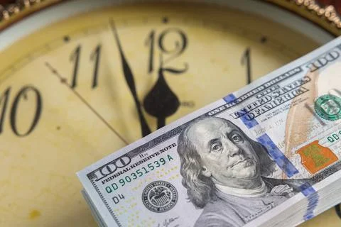 Stack of US hundred dollar bills on vintage clock face background concept o.. Stock Photos