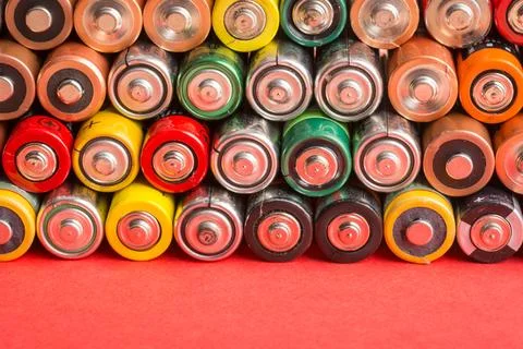 Stack of used batteries on a red background 写真素材