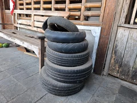 Stack of used black rubber tires on stone floor of garage workshop. Stock Photos